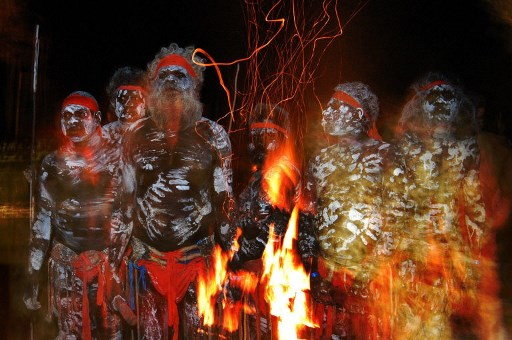 White Cockatoo Performing Group, from communities across Arnhem Land, keep warm in front of an open fire during The Dreaming — Australia’s International Indigenous Festival. — AFP pic